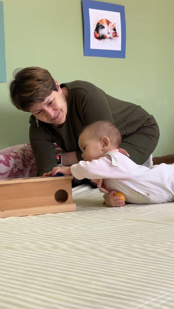 Murabbiy kuzatib turganda yog'och imbucare qutisi bilan shug'ullanayotgan chaqaloq